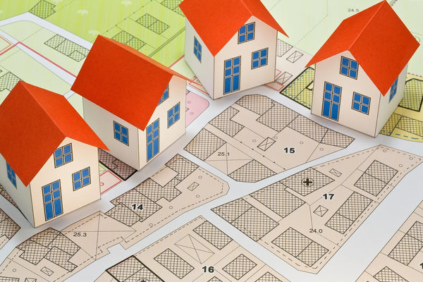 stock image of miniature houses placed on a paper plan