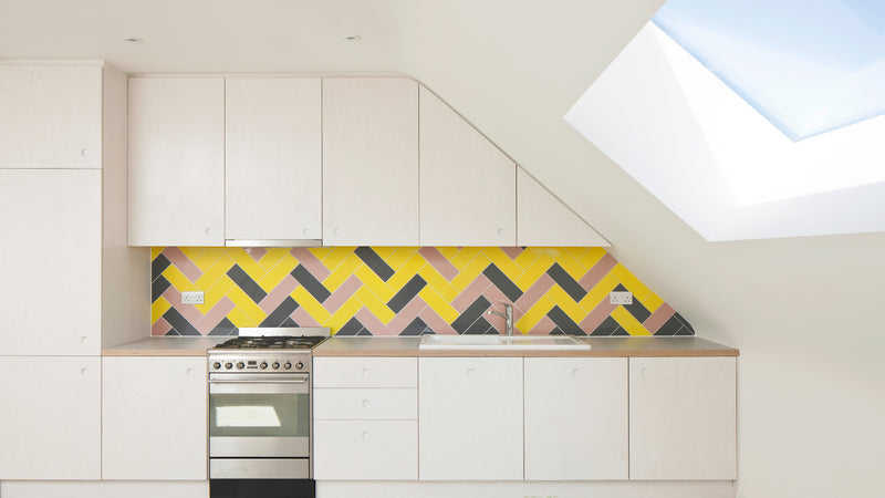 roof window installed in a light, modern kitchen with grey and yellow splashback and white furnishings 