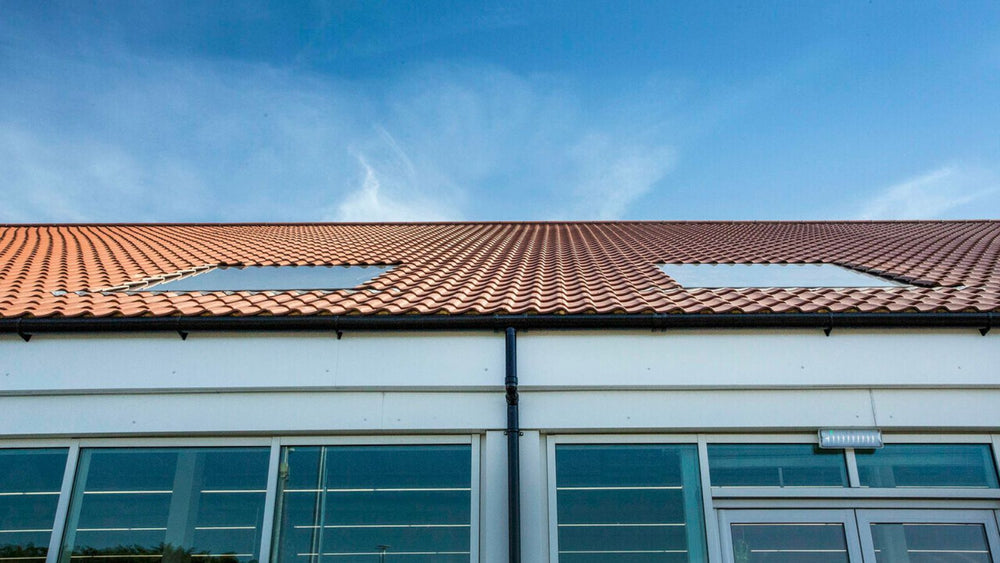 two roof windows installed on the tiled roof of a commercial shop