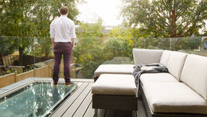 man in burgandy trousers standing at the edge of a walk on rooflight on a roof terrace 